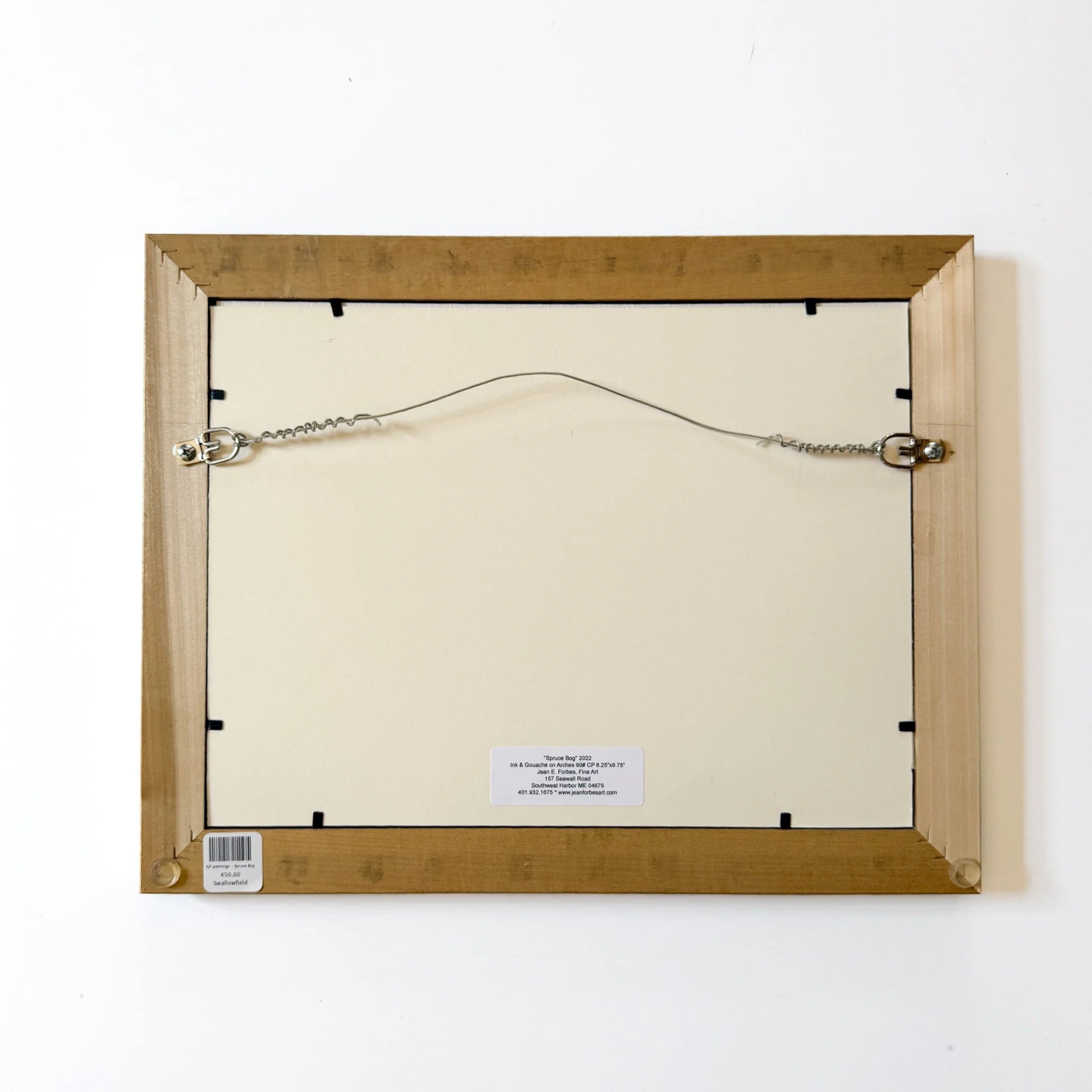 Back view of a wooden picture frame with a white mat and a visible hanging mechanism.